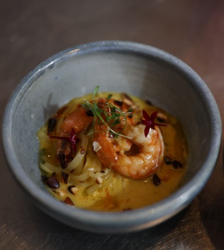 Crevettes et nouilles de tayota dans une sauce dorée, servies dans un bol