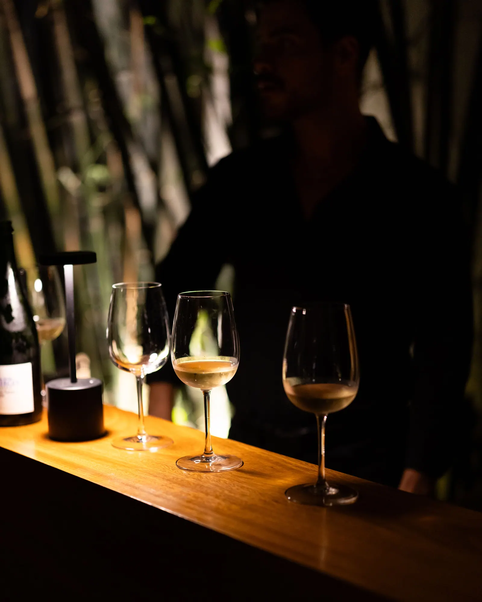 Wine glasses and a small lamp on a wooden table